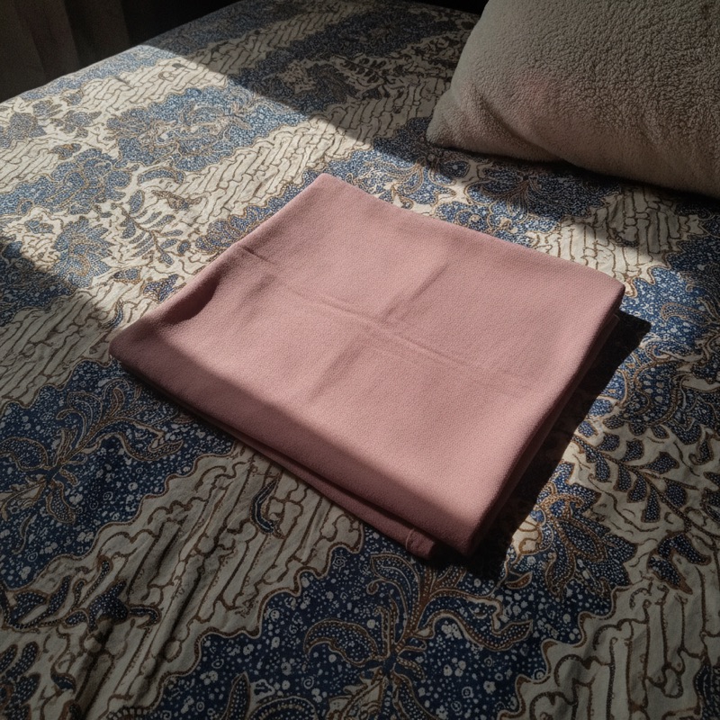 Pashmina terlipat di atas seprai batik
